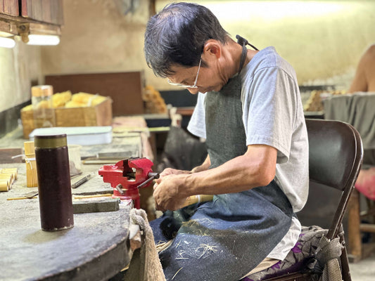 Craftsman making a traditional matcha whisk handmade with precision and care in a workshop setting